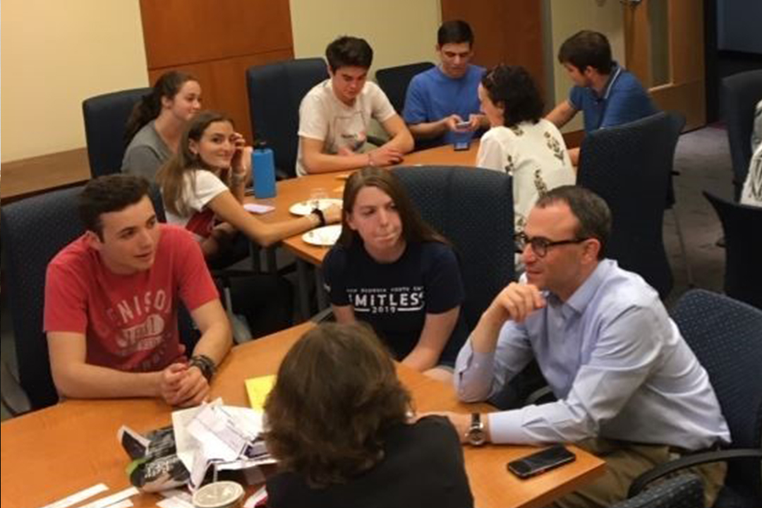students gather around two tables to speak Hebrew