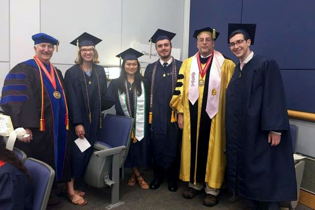 A group of students and teachers in caps and gowns. From left, Prof. Eric Cline, Sydney Thatcher, Harper Hansen, William Berkery, Prof. Chris Rollston, and Jonah Bannett.