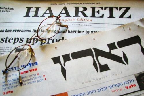 Copies of Haartz newspaper in english and hebrew editions with reading glasses