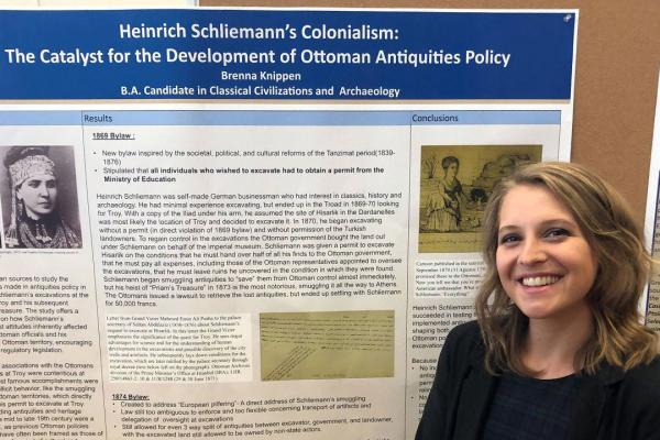 Student Brenna Knippen stands in front of her research poster on Heinrich Schliemann’s Colonialism: The Catalyst for the Development of Ottoman Antiquities Policy