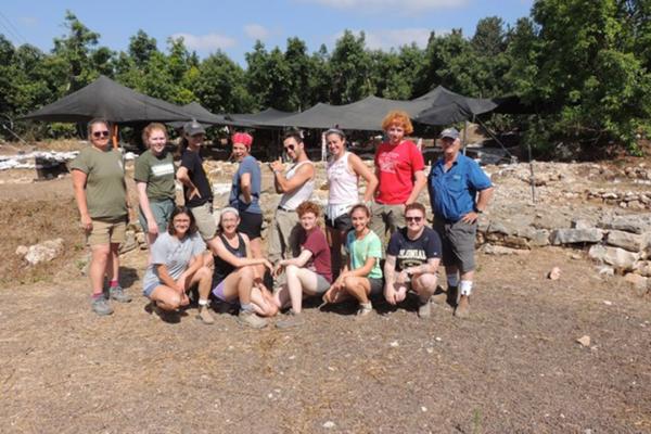 Eric Cline with a group of GW students standing outside tents at a dig site in Tel Kabri